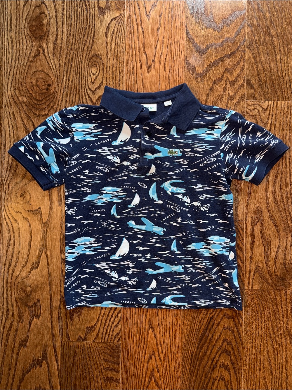Boys Lacoste polo. Navy with blue & white sailboat and airplane pattern.